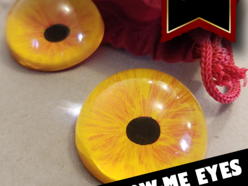 Orange eyes on a table beside a red velvet bag